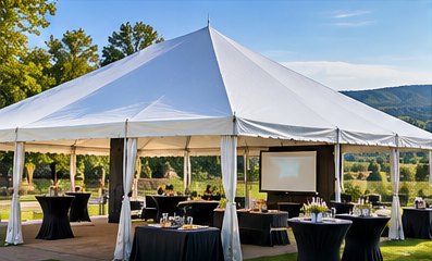 Tent with cocktail tables and a projector screen for a company event